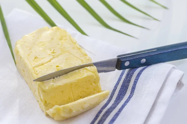 Butter. Scheibe Butter. frische geschnittene Butter auf Teller auf weißem und grünem Hintergrund — Stockfoto