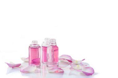 Bir şişe beyaz zemin üzerine gül yaprakları ile gül uçucu yağ