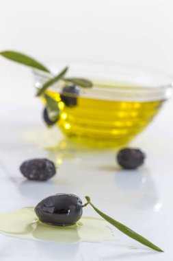 Organik zeytin yağı ve nitelikleri zeytin ile cam kase beyaz arka plan üzerinde bırakır