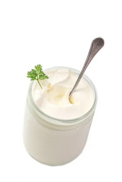 Primo piano di pentola di crema aspra con cucchiaio e prezzemolo in su sfondo bianco vista dall'alto — Foto Stock