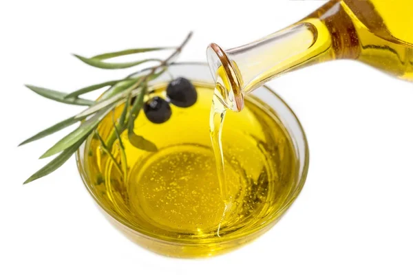 Olio d'oliva versando in ciotola da una bottiglia e frutta matura su fondo bianco — Foto Stock
