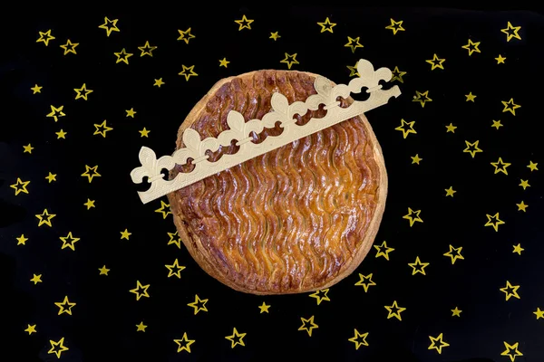 Galette des rois, torta di re francese con corona d'oro su sfondo nero con stella dorata — Foto Stock