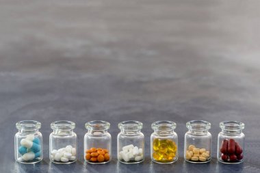 Tıp kavramı: Tıp tablet doğrultusunda multi ile açılan cam şişe plastik kapaklar arduvaz arka plan üzerinde renkli.