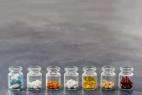 Conceito de Medicina: linha de Medicina Tablets em vidro aberto Garrafa com tampas plásticas multicoloridas em fundo de ardósia — Fotografia de Stock
