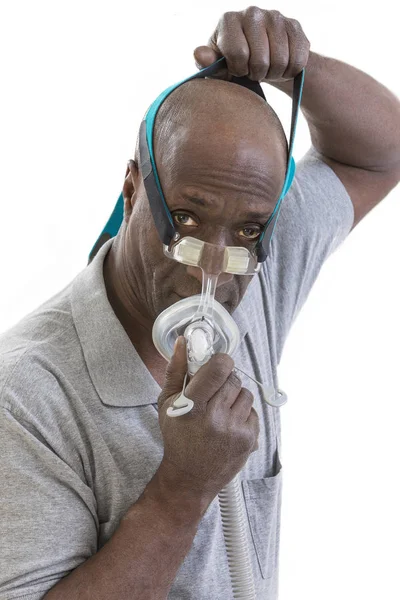 Når en mann med en søvnforstyrrelse prøver seg på en Cpap for første gang, lærer han å justere CPAP-utstyret sitt på hvit bakgrunn – stockfoto