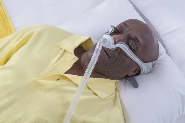 Gesundheitskonzept, afrikanisch, amerikanisch Mann mit obstruktiver Schlafapnoe schlafend gut mit cpap Maschine, Mann im Bett liegend mit cpap Maske, auf weißem Hintergrund — Stockfoto