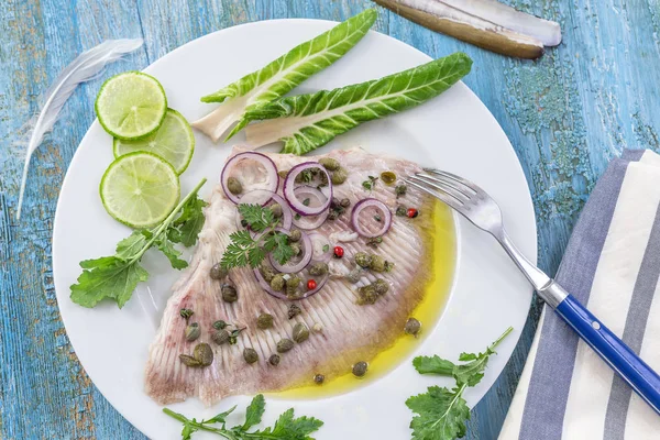 Ala skate al vapore con olio di oliva cappero su sfondo blu in legno — Foto Stock