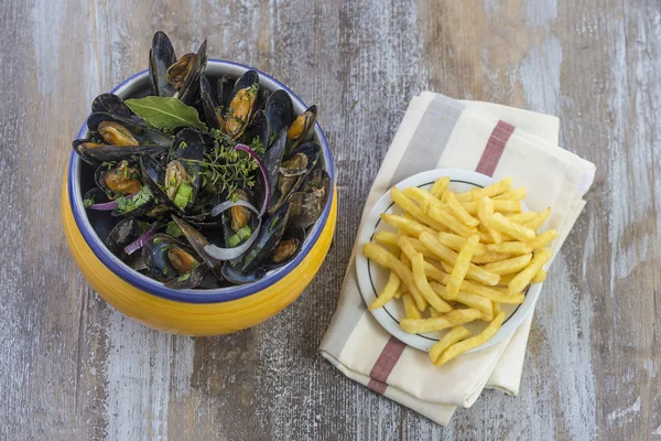 Fransız mavi midye otlar patates kızartması cam ramekin peçete deniz ürünleri ahşap tahta arka planda üzerinde sarı bir kase ile — Stok fotoğraf