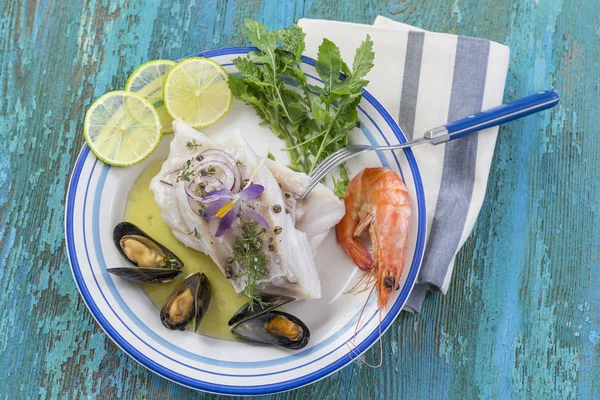 Filé de bacalhau, bacalhau atlântico com mussells de frutos do mar, camarões, lima e legumes, sobre fundo de madeira azul — Fotografia de Stock