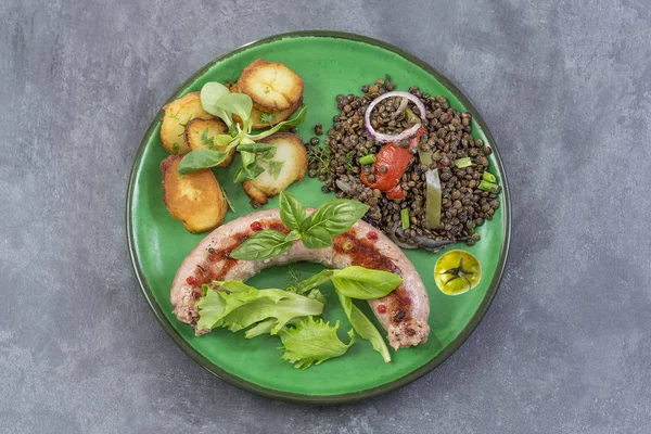 Fransa Toulouse ızgara sosis kavrulmuş potatoaes ve salata ve mercimek gri arka plan üzerinde