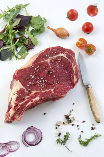 Pohled shora na syrové T-bone Steak na grilu nebo Bbq na prkénku s nožem nad na bílém podkladě, — Stock fotografie