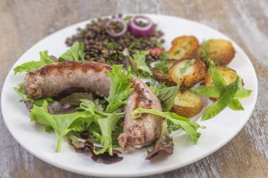 Fransa Toulouse ızgara sosis kavrulmuş potatoaes ve salata ve mercimek eski ahşap zemin üzerine