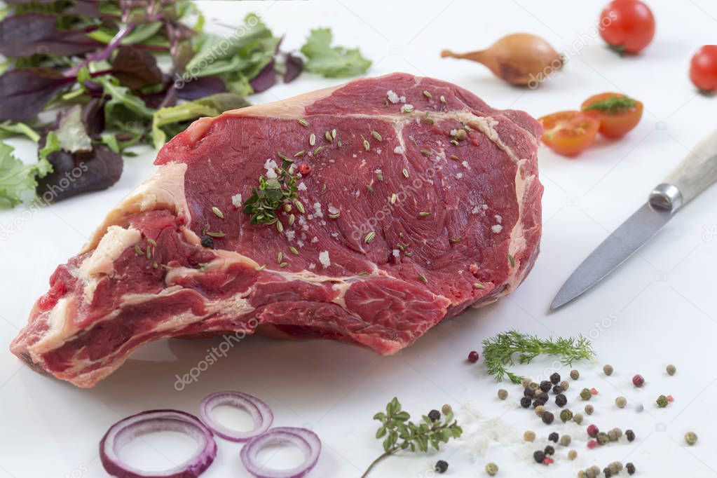 Raw T-bone Steak for grill or BBQ on cutting board with knife over on a white background, top view