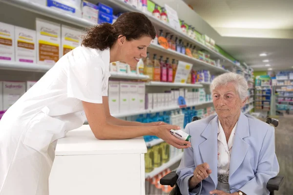 female pharmacist taking prescription from disabled woman wheelchair in a pharmafy