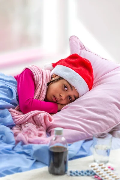 Niña pequeña con sombrero de Santa recibir su regalo mientras está en el hospital o en casa —  Fotos de Stock