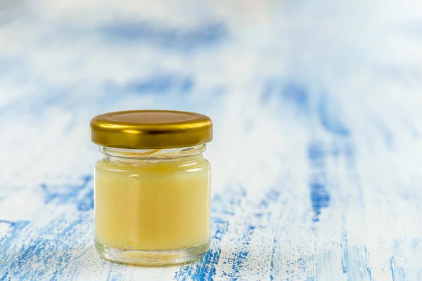Rå ekologisk kunglig gelé i en liten flaska, kunglig gelé. Guld, biodling. över blå ooden bakgrund — Stockfoto
