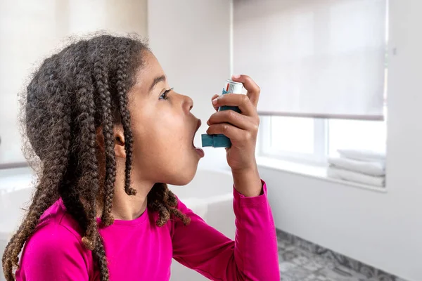 Retrato de cerca de una linda niña de 5 años usando su inhalador de asma, vista de perfil fondo blanco — Foto de Stock