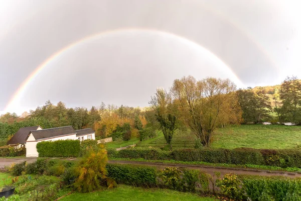 A traditional French house is framed by a rainbow over countryside in Bernay, Normandy, France, October, 25, 2019 — стоковое фото