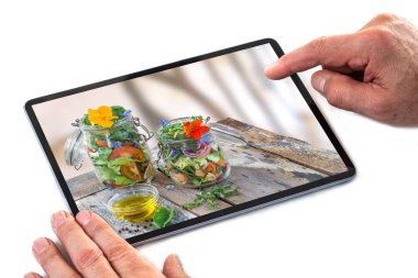 Adam, sebze, salata, domates ve somon balığı ve yenilebilir çiçek fotoğrafı için tablet bilgisayar ekranını kaydırıyor. Öğle yemeği, akşam yemeği, sağlıklı beslenme
