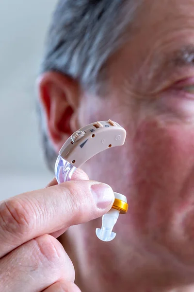 Leder for en overordnet mann som setter inn høreapparat i øret hans – stockfoto
