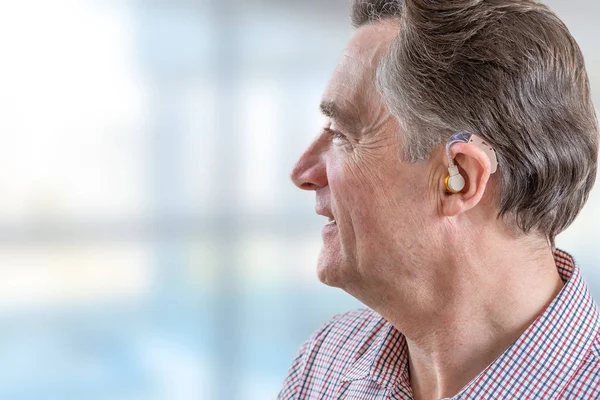 Head of a senior man with hearing aid in his ear — Stock Photo, Image