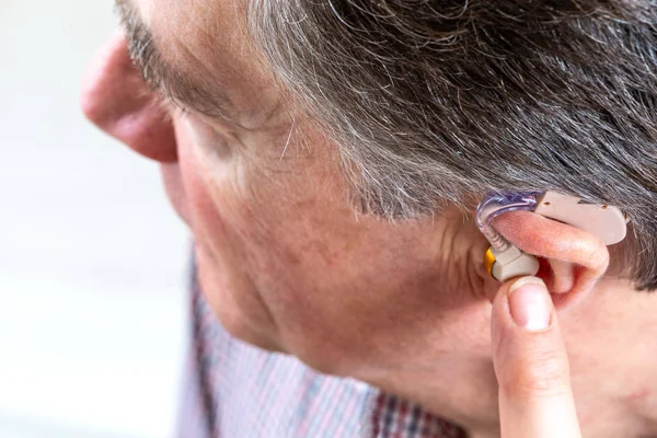 Head of a senior man showing hearing aid in his ear — Stock Photo, Image