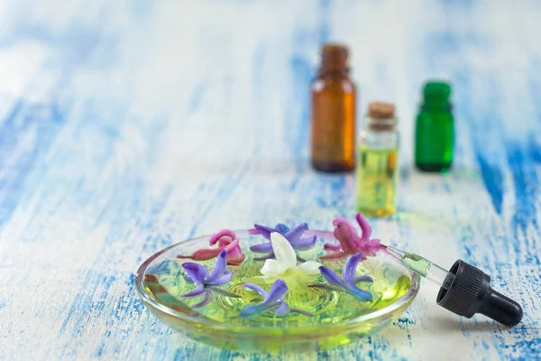 Сине-белый и розовый фловеры гиацинта в керамической миске с капельницей эфирного масла и бутылкой на заднем плане — стоковое фото