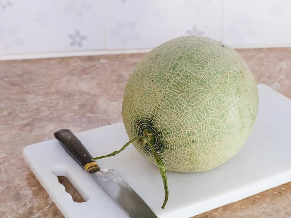 Mutfak bıçağıyla beyaz bir blok üzerinde yeşil Japon kavun