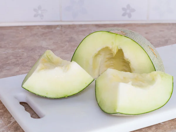 Green japanese melon was cut or divided on a white block in kitc