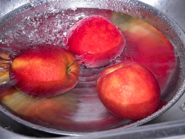 Mele rosse in acqua, in ciotola di acciaio inox con una goccia d'acqua — Foto Stock