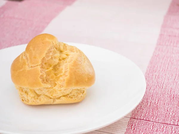 Kremalı pasta üzerinde beyaz tabak, pembe masa örtüsü