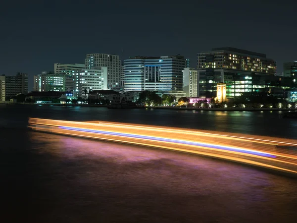 Nehir ve bir portakal tekne mavi ışık hattı ile yakın bina