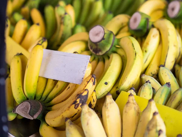 Plátano fresco natural maduro con pancarta blanca, en el mercado . — Foto de Stock