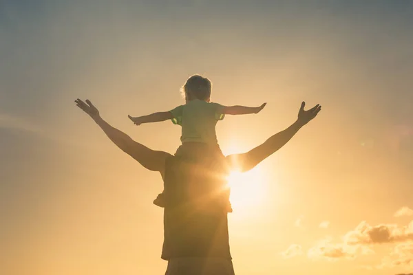 腕のある幸せな父と息子は 日没の空に対して一緒に演奏を伸ばしました 腕を自由に感じて — ストック写真