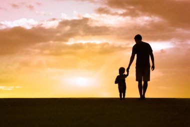 Baba oğul gün batımında yürüyorlar. Aile kavramı. 