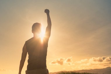 Güçlü, yumruğu havada bir dağın tepesinde duran adam.. 