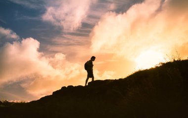 Dağın tepesine tırmanan bir adam. 