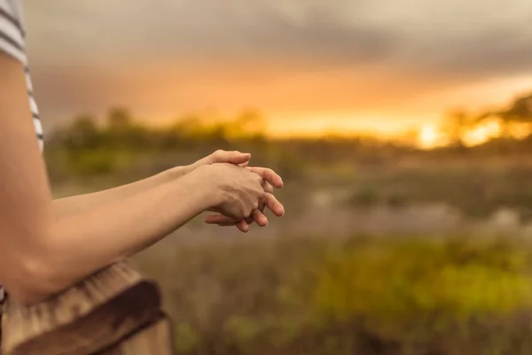 Young woman relaxing next to open field watching the beautiful sunrise. Peace of mind, nature getaway concept.