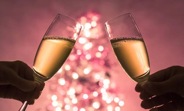 People cheering with champagne next to the Christmas tree.