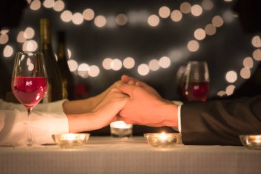 Romantik bir akşam yemeği için el ele tutuşan bir çift. Randevu gecesi,
