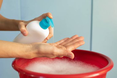 Kadın ellerini sabunla yıkıyor.