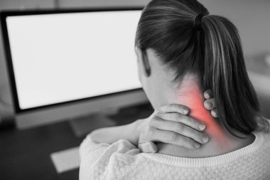 Ofis masasında oturan genç bir kadın boynu ağrıdığı için acı çekiyor..