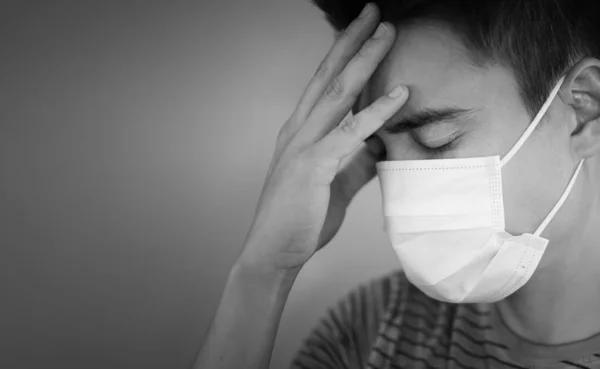 若い男は顔の保護マスクで病気のストレスを感じている コロナウイルスの症状と精神衛生の概念 — ストック写真