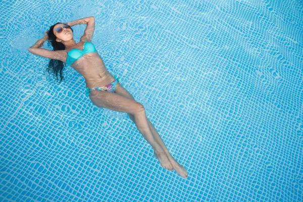 Menina sexy toma um banho de sol na piscina — Fotografia de Stock