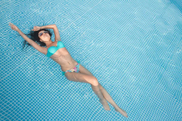 Foto de moda de menina bonita sexy com cabelo morena em biquíni elegante toma um banho de sol na piscina — Fotografia de Stock