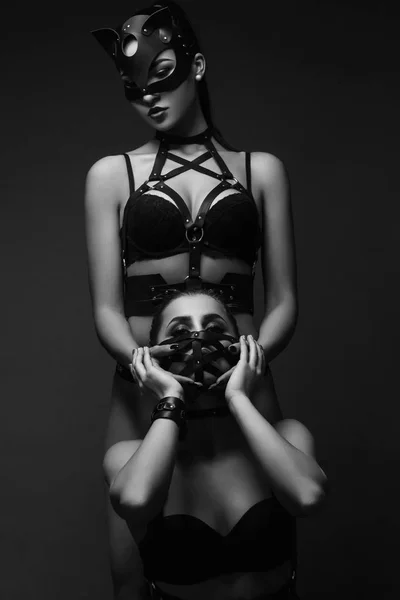 Two sexy girls in masks and leather belt (black and white photo) — Stock Photo, Image