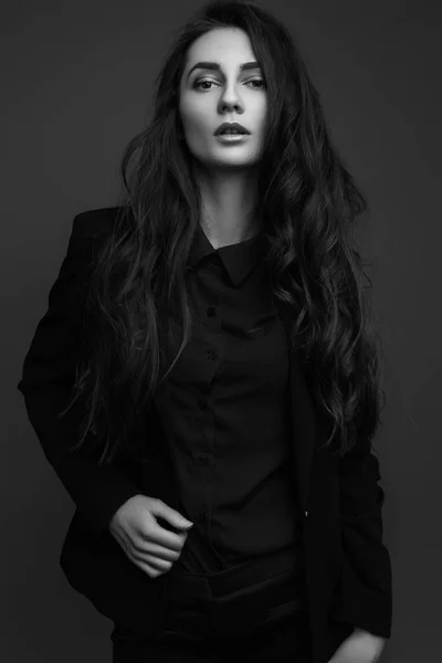 Красива дівчина з довгим волоссям у класичному чорному костюмі та позуванні сорочки. чорно-біле зображення — стокове фото