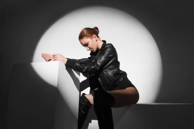 Stüdyoda deri ceketli güzel bir kız oturuyor.