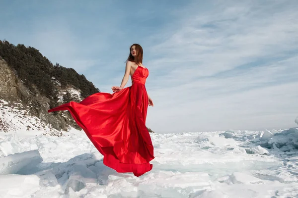 一个穿着红色长裙的漂亮姑娘站在冰冻的贝加尔湖冰上 — 图库照片