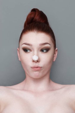 Yüzünde krem şanti olan güzel bir kızın portresi.